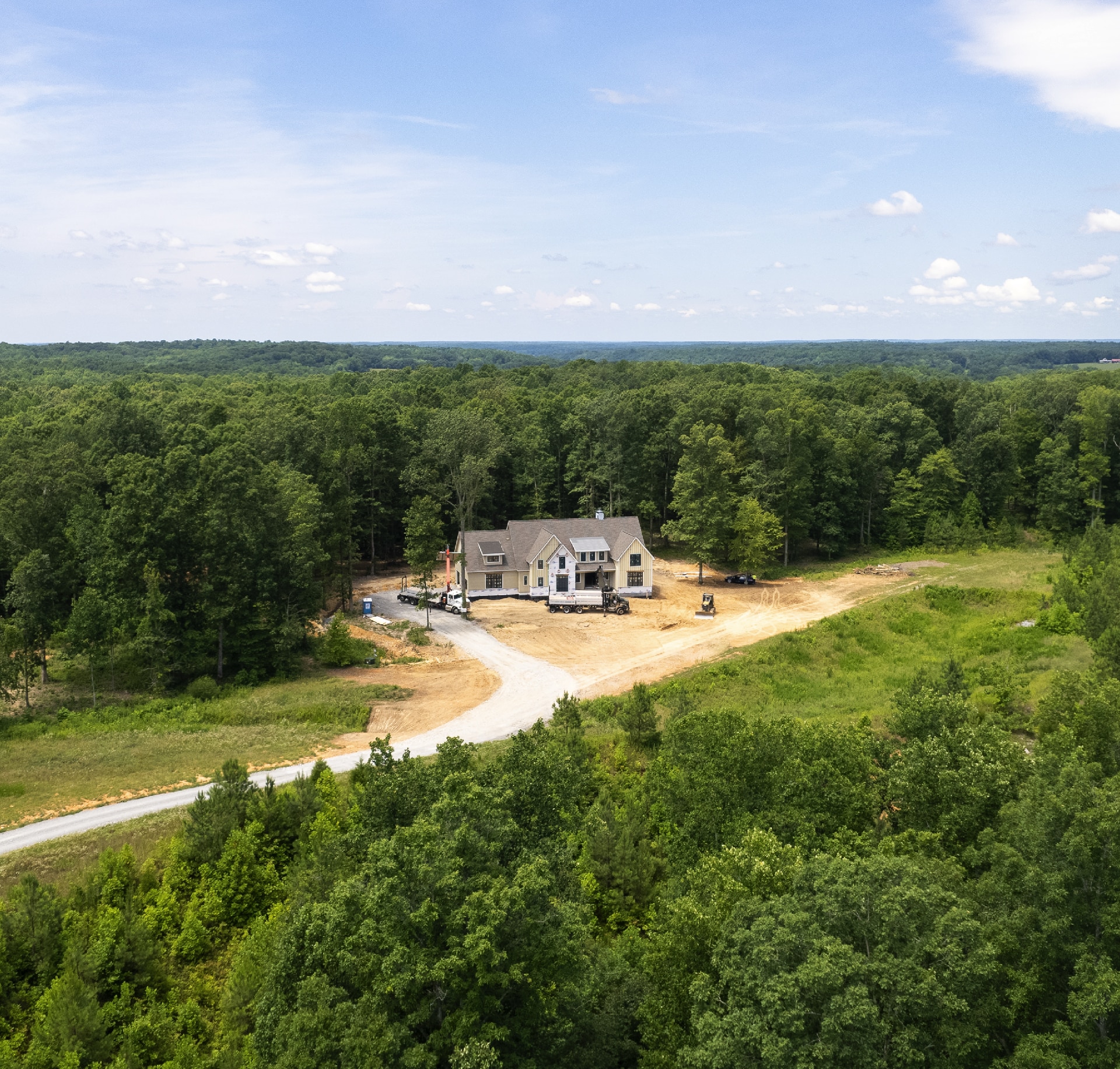 Aerial view of a luxury custom home under construction on a wooded lot in Middle Tennessee by Hewn Custom Homes.